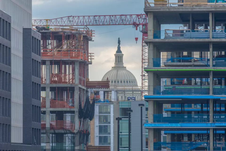 View of Washington D.C. Capitol dome through high-rise buildings in various states of construction.